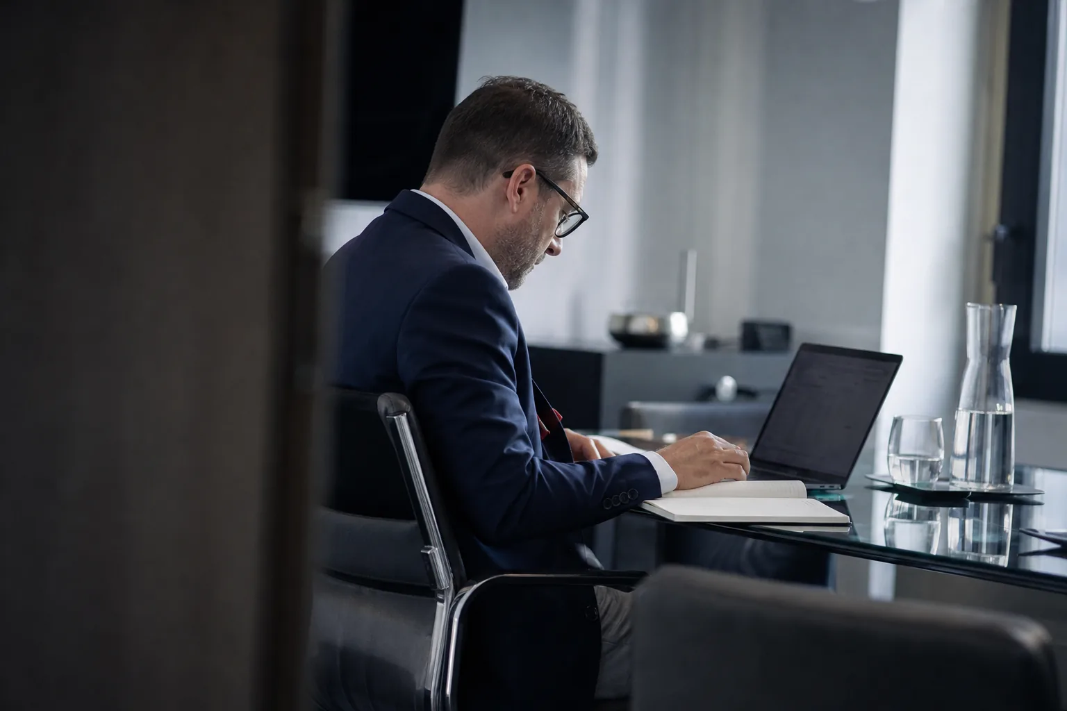 Przedsiębiorca w gabinecie zarządu analizuje transakcję na laptopie