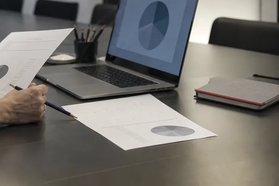 Sprawozdanie z wykresem kołowym i laptop z podziałem udziałów na stole konferencyjnym